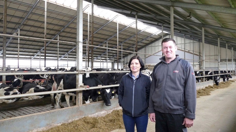 Photo of Anna Adamczuk together with one of Polish farmer in front of cows in a barn.